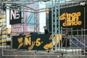 DJ NUS (nus_music) aus Bonn ist ein junger Newcomer-DJ auf der Techno und House Stage des SMAG SunDance Open Air Festivals in Essen am 13.07.2024 neben Artists wie Pretty Pink, Felix Kröcher oder Simona Grigoriu und Felix Jaehn. "NUS" ist der Künstlername von Linus Moog, der vor allem als Schauspieler bekannt ist und sich seit 2018 unter seinem Pseudonym als junger, leidenschaftlicher und aufstrebender Newcomer-DJ und Künstler in seiner Heimatstadt Bonn und darüber hinaus einen Namen in der elektronischen Musikszene gemacht hat: Im Dezember 2023 wurde NUS in der FAZEmag-Liste "Aufstrebende Stars der deutschen elektronischen Musikszene: Newcomer, die man im Auge behalten sollte" erwähnt. Er beschreibt seine musikalische Ausrichtung als "minimal Techno-House": Das ist kraftvoller & melodischer Techno, kombiniert mit einem Hauch von unkommerziellem Tech-House und einer kleinen Nuance von House. Das markanteste Merkmal - abgesehen von seinem jungen Alter - ist seine Trackauswahl: Er versucht meist sehr unbekannte Tracks zu spielen, mit denen er auch große Szenekenner beeindrucken und überraschen kann. Das alles macht ihn und seinen Sound absolut einzigartig, tanzbar und hörenswert. Dies hat er bereits auf einigen Veranstaltungen bewiesen, wo er Publikum & Veranstalter begeistern konnte: Anfang 2024 gewann er den renommierten DJ-Contest des "Tante Mia Tanzt Festivals" in Vechta sowie im gleichen Jahr ebenfalls den DJ Contest des „SMAG SunDance Festivals“ in Essen. Außerdem spielte er Gigs beim "Panama Open Air Festival", beim "Telekom Open Air", dem "Green Juice Festival", "Rhein In Flammen", "Odonien Köln" und beim "Bikini Beach Bonn". Seine Sets wurden u.a. bei Dit Klingt Jut, Jeden Tag ein Set und Tagesraver veröffentlicht. Darüber hinaus war NUS in der lokalen Presse präsent und erschien in Berichten und Artikeln des General-Anzeigers Bonn, der WDR Lokalzeit Bonn, des Radiosenders Radio Bonn/Rhein-Sieg und der Tageszeitung Express - Inzwischen hatte NUS die große Ehre, vor international renommierten Künstlern wie Kölsch, Felix Jaehn, ARTBAT, Pretty Pink, Tube&Berger, David Puentez, Felix Kröcher, Oliver Schories, Pappenheimer & Oliver Huntemann auftreten zu dürfen.