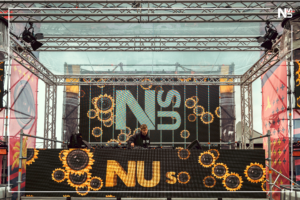 DJ NUS (nus_music) aus Bonn ist ein junger Newcomer-DJ auf der Techno und House Stage des SMAG SunDance Open Air Festivals in Essen am 13.07.2024 neben Artists wie Pretty Pink, Felix Kröcher oder Simona Grigoriu und Felix Jaehn. "NUS" ist der Künstlername von Linus Moog, der vor allem als Schauspieler bekannt ist und sich seit 2018 unter seinem Pseudonym als junger, leidenschaftlicher und aufstrebender Newcomer-DJ und Künstler in seiner Heimatstadt Bonn und darüber hinaus einen Namen in der elektronischen Musikszene gemacht hat: Im Dezember 2023 wurde NUS in der FAZEmag-Liste "Aufstrebende Stars der deutschen elektronischen Musikszene: Newcomer, die man im Auge behalten sollte" erwähnt. Er beschreibt seine musikalische Ausrichtung als "minimal Techno-House": Das ist kraftvoller & melodischer Techno, kombiniert mit einem Hauch von unkommerziellem Tech-House und einer kleinen Nuance von House. Das markanteste Merkmal - abgesehen von seinem jungen Alter - ist seine Trackauswahl: Er versucht meist sehr unbekannte Tracks zu spielen, mit denen er auch große Szenekenner beeindrucken und überraschen kann. Das alles macht ihn und seinen Sound absolut einzigartig, tanzbar und hörenswert. Dies hat er bereits auf einigen Veranstaltungen bewiesen, wo er Publikum & Veranstalter begeistern konnte: Anfang 2024 gewann er den renommierten DJ-Contest des "Tante Mia Tanzt Festivals" in Vechta sowie im gleichen Jahr ebenfalls den DJ Contest des „SMAG SunDance Festivals“ in Essen. Außerdem spielte er Gigs beim "Panama Open Air Festival", beim "Telekom Open Air", dem "Green Juice Festival", "Rhein In Flammen", "Odonien Köln" und beim "Bikini Beach Bonn". Seine Sets wurden u.a. bei Dit Klingt Jut, Jeden Tag ein Set und Tagesraver veröffentlicht. Darüber hinaus war NUS in der lokalen Presse präsent und erschien in Berichten und Artikeln des General-Anzeigers Bonn, der WDR Lokalzeit Bonn, des Radiosenders Radio Bonn/Rhein-Sieg und der Tageszeitung Express - Inzwischen hatte NUS die große Ehre, vor international renommierten Künstlern wie Kölsch, Felix Jaehn, ARTBAT, Pretty Pink, Tube&Berger, David Puentez, Felix Kröcher, Oliver Schories, Pappenheimer & Oliver Huntemann auftreten zu dürfen.